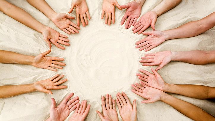 Circle of hands in sand
